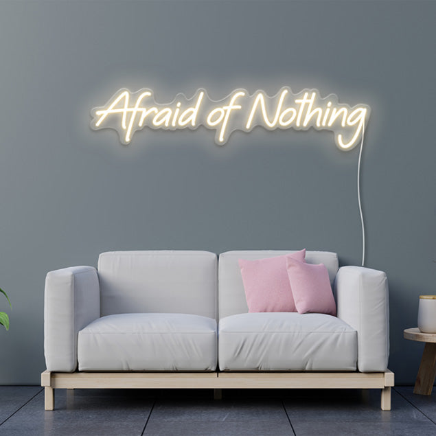 Afraid of Nothing pre-designed CUSTOM NEON® sign shown in warm white on light grey wall above a couch