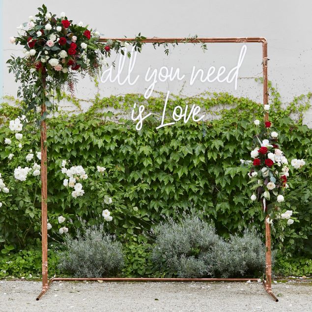 Large All You Need is Love white LED neon sign shown on frame at wedding of @georgiealove & @leeroyelliot - made by Custom Neon®
