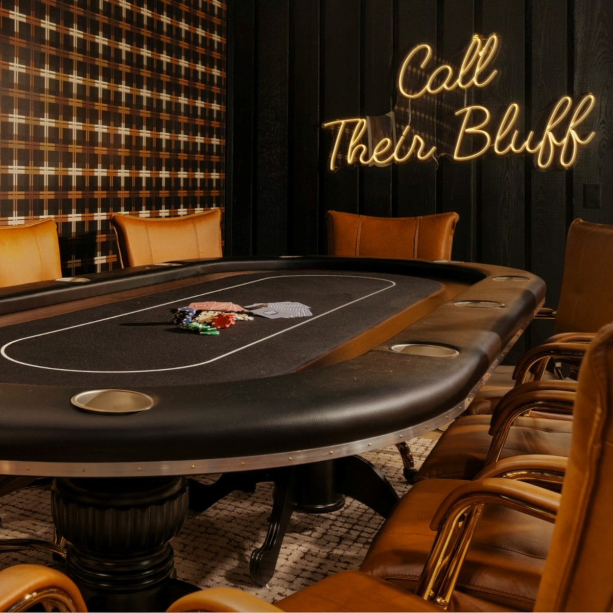 Call Their Bluff LED neon sign on a dark wooden wall behind a gaming table in a masculine room decorated in tans