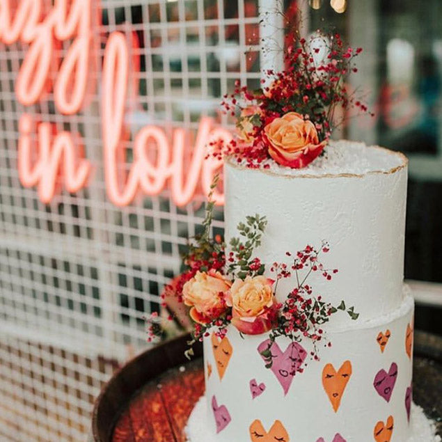 Crazy in Love LED neon wedding sign shown on mesh with a wedding cake in the foreground - photo from Custom Neon