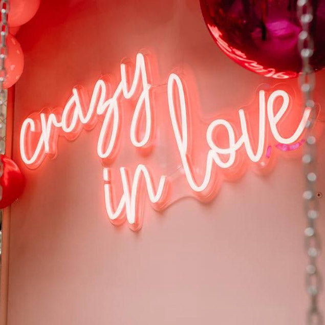 Crazy in Love LED neon light shown mounted on a wall with balloons - photo from CustomNeon.com