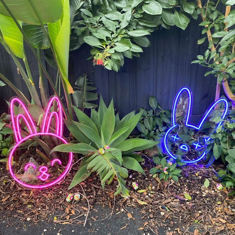 Custom Neon® pink bunny face and blue bad bunny face shown as lighted decor for an Easter egg hunt
