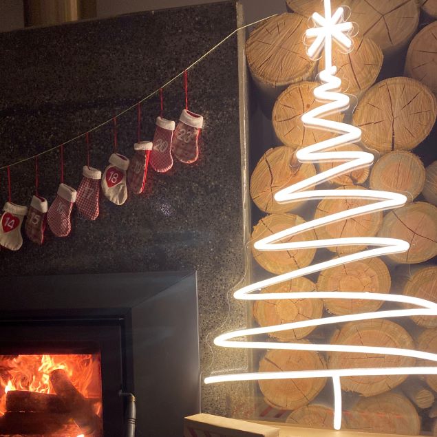 White LED neon Christmas tree pictured with a modern fireplace, logs, Christmas stockings & presents - by CUSTOM NEON®