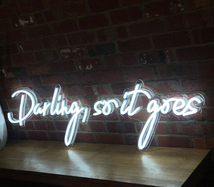 so it goes Neon Sign Quote for Weddings & Home Decor shown on green wall
- photo from CustomNeon.com