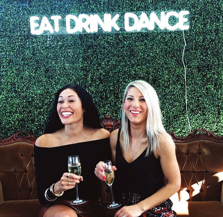 * Eat Drink Dance * Portable LED Neon Light Sign shown on a green wall at an Event - photo from CustomNeon.com
