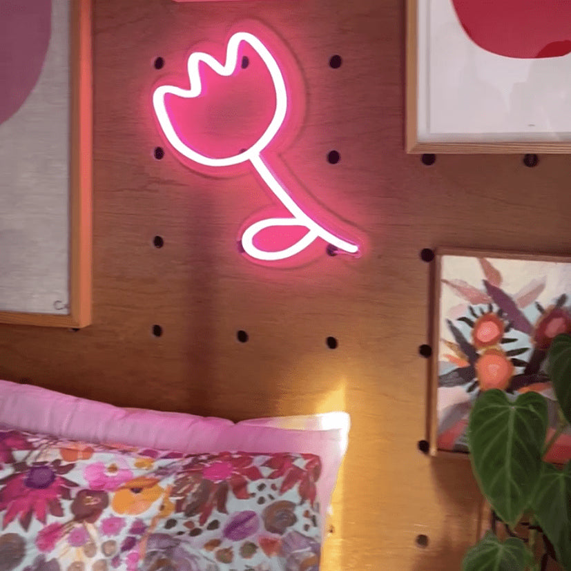 Custom Neon® pink flower mounted on a wooden peg board bedroom wall