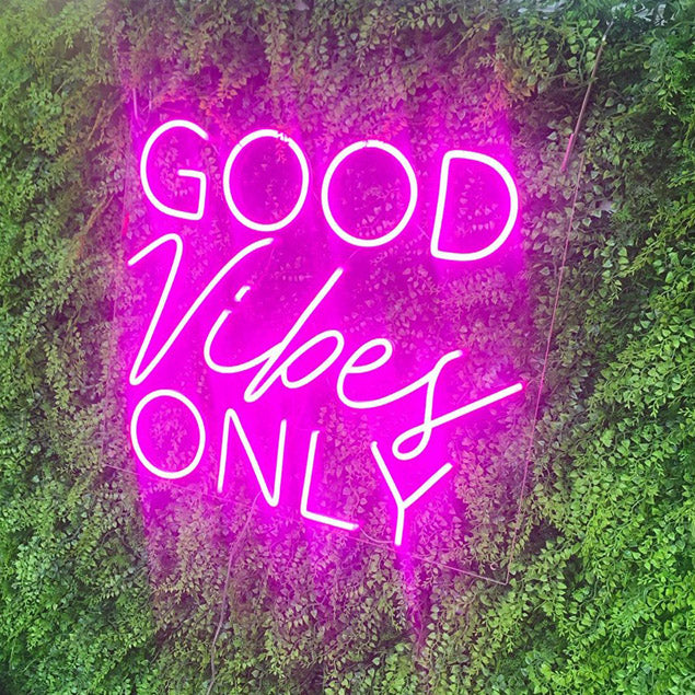Good Vibes Only Trendy LED Neon Light in Two Fonts shown in pink on green wall from Custom Neon®