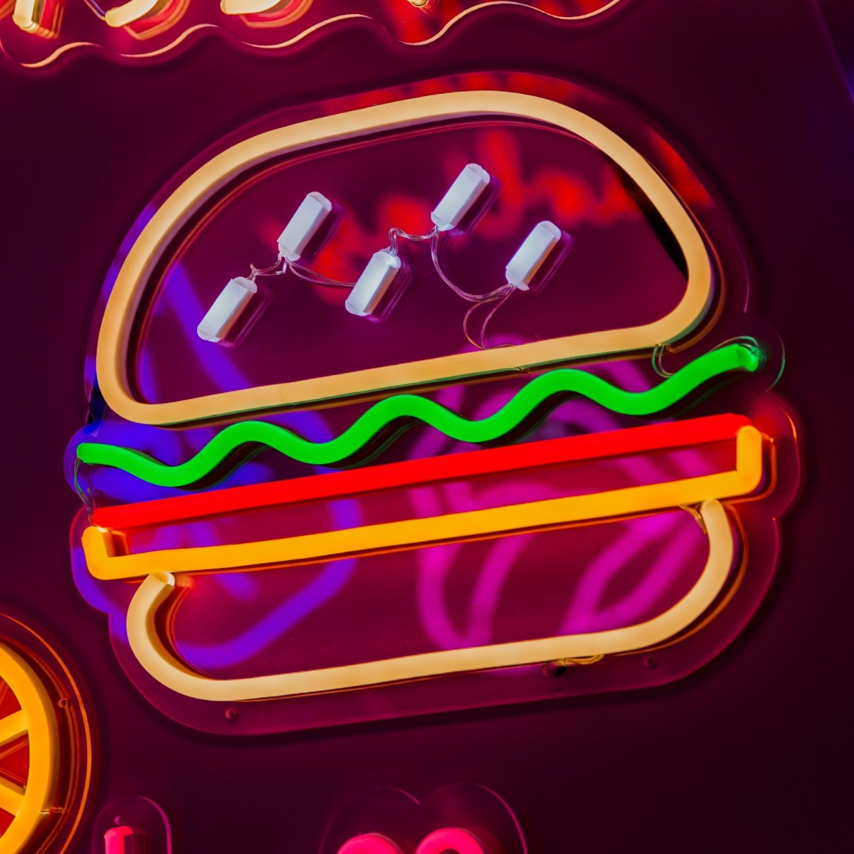 Custom Neon® food sign: Hamburger with the Lot shown illuminated against a dark wall in dim light