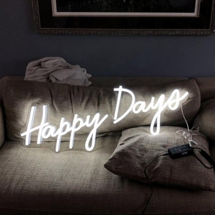 Happy Days LED neon sign shown illuminated on a couch - photo CustomNeon.com