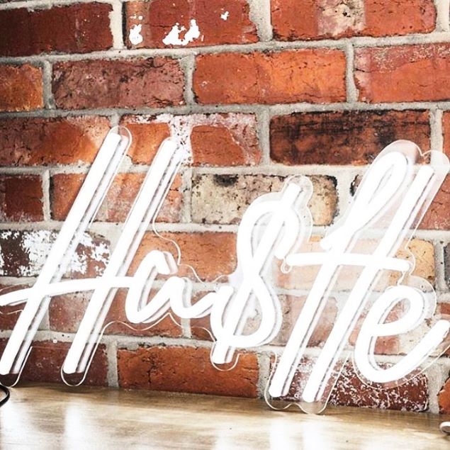 Hustle light sign against an exposed brick wall - from Custom Neon