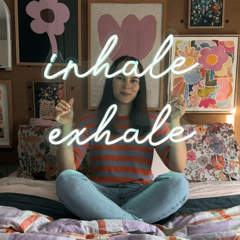 Custom Neon® white Inhale Exhale sign shown in a bedroom,Inhale Exhale Custom Neon® wall sign shown illuminated on a white wall,Inhale Exhale Custom Neon® wall sign shown illuminated on a living room wall
