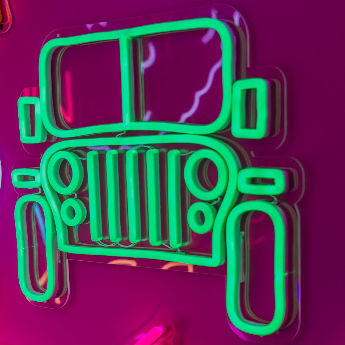 CUSTOM NEON® Garage Signs: Green Jeep LED wall art shown illuminated against a dark background in dim light