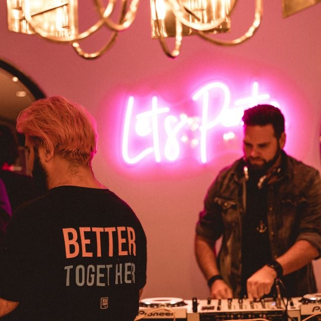 Let's Party pink LED neon sign behind the DJ at a nightclub event by @customneon for @thesocial.agency
