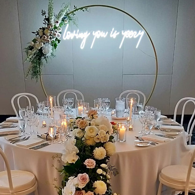 Loving you is yeezy LED neon light shown attached to a floral arch behind the top table - photo from CustomNeon.com