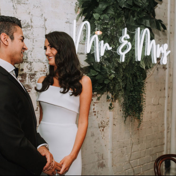Mr & Mrs portable LED neon sign on clear acrylic backboard. Shown on exposed brick wall. - Photo CustomNeon.com