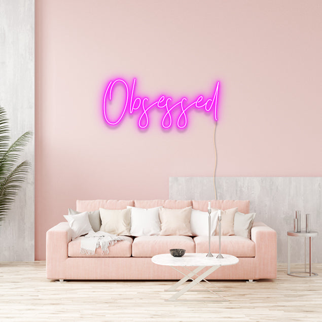 Obsessed LED neon wall art in pink above a couch - from Custom Neon