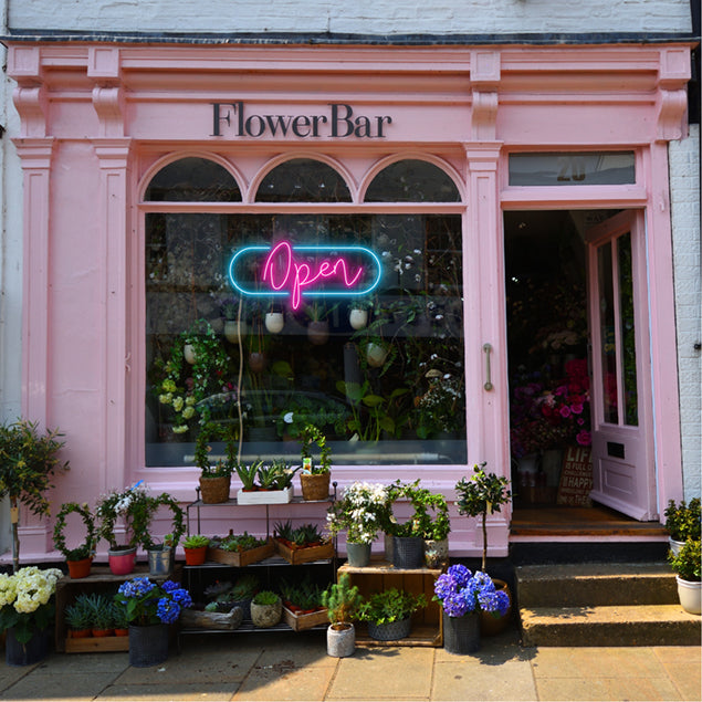 LED Neon Flex open sign in a modern cursive font surrounded by an oblong frame shown in a florist's shop window - from CustomNeon.com