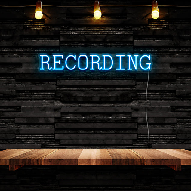 CUSTOM NEON® electric blue Recording light in a serif font against a dark wall
