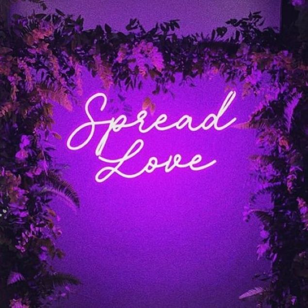 Spread Love neon flex sign shown surrounded by florals at an event - from Custom Neon
