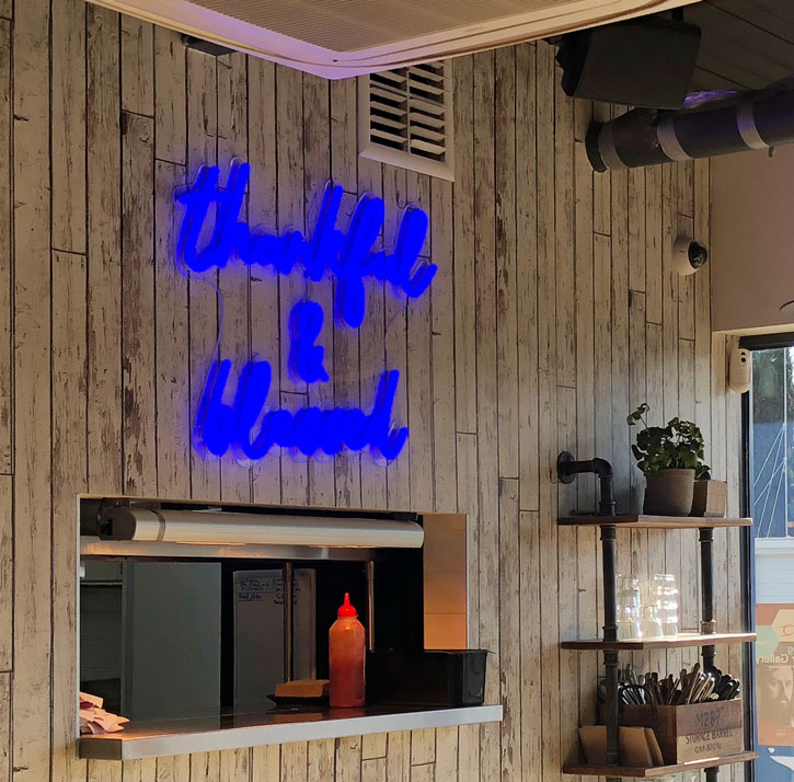 Thankful & Blessed LED Neon Sign shown in a cafe mounted above the serving counter - photo from Custom Neon