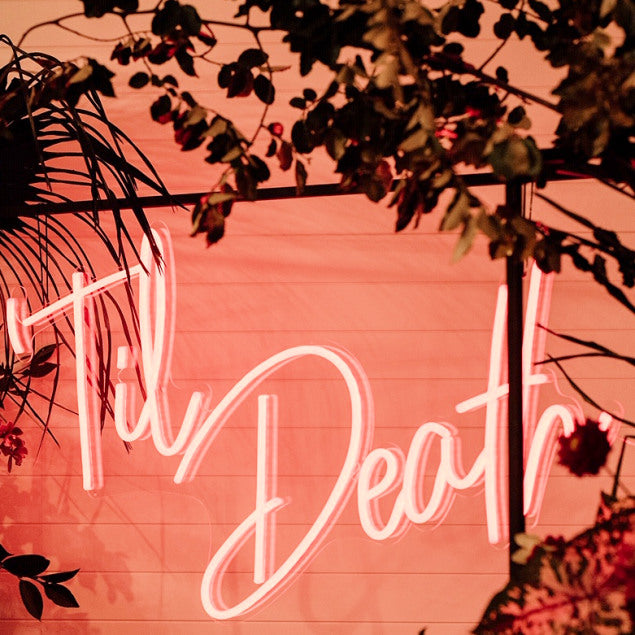 Til Death LED neon sign shown hanging from a frame at a wedding - photo from CustomNeon.com