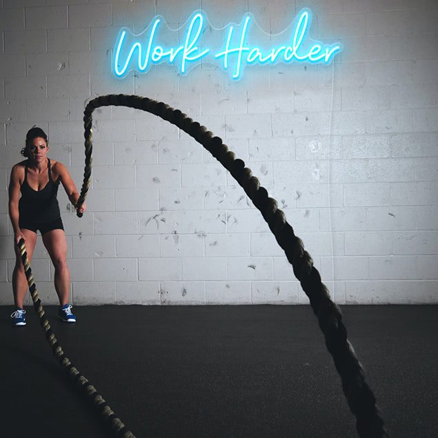 Work Harder light blue CUSTOM NEON® signs on brick wall in fitness/boxing studio