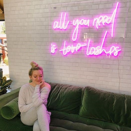 All You Need is Love Lashes pink light sign mounted to a brick wall in a lash bar - made @customneon
