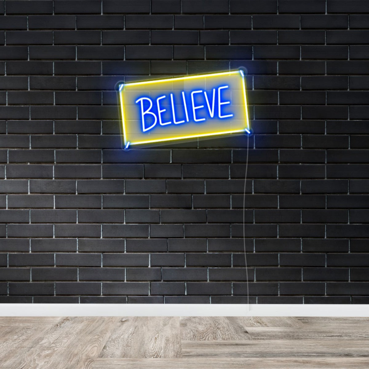 Believe Custom Neon® sign in dark blue and yellow shown against a dark brick wall