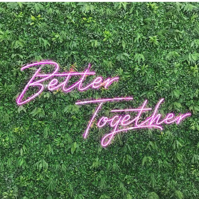 Better Together purple LED neon sign shown on a living green wall at an event - from CustomNeon.com