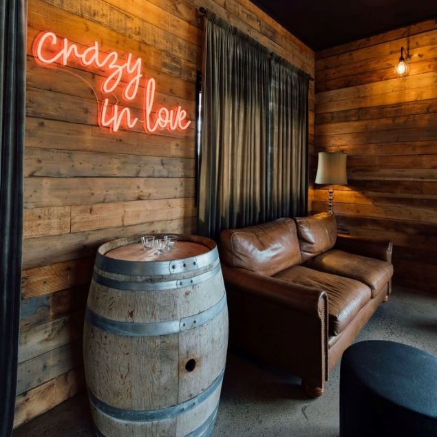 Crazy in Love neon flex light sign mounted on a wooden wall above a wine barrel at a rustic wedding @rocklea_farm - from Custom Neon