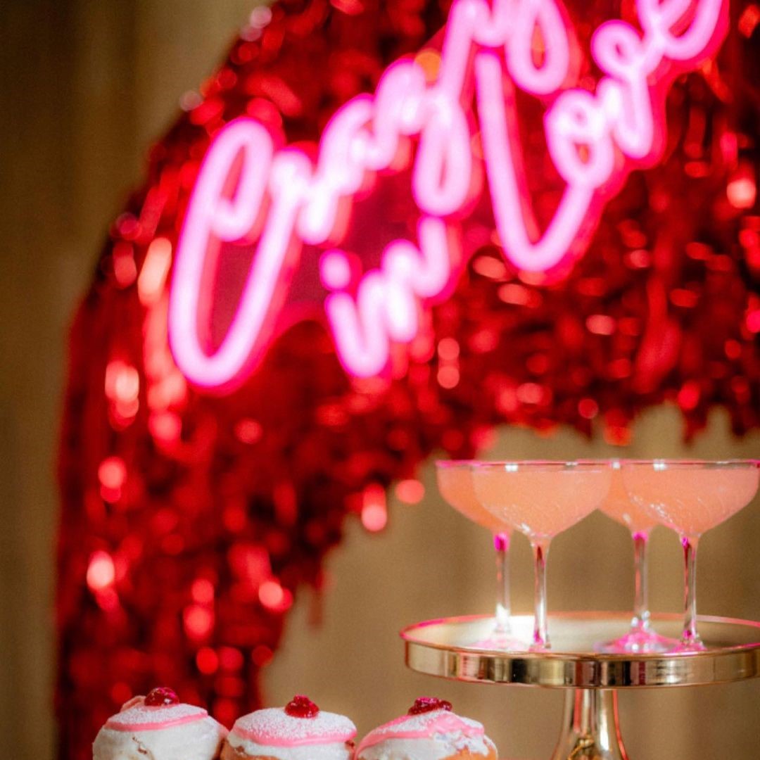Crazy In Love Wedding Sign in brilliant LED neon flex shown in pink with wedding florals and cakes - photo from CustomNeon.com