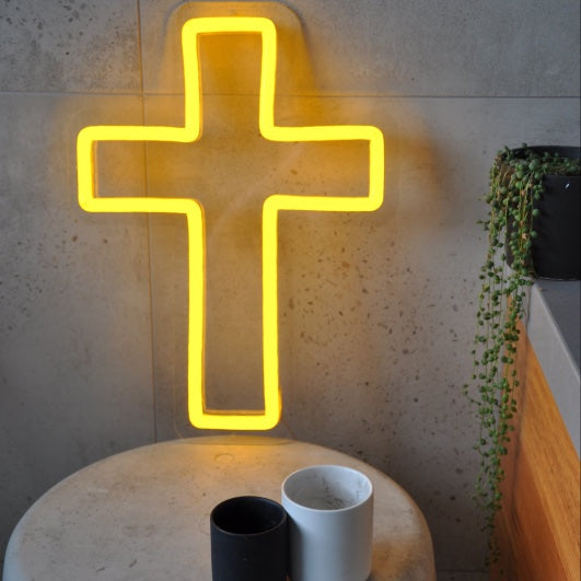 LED neon cross shown illuminated in yellow on a side table - photo from CustomNeon.com