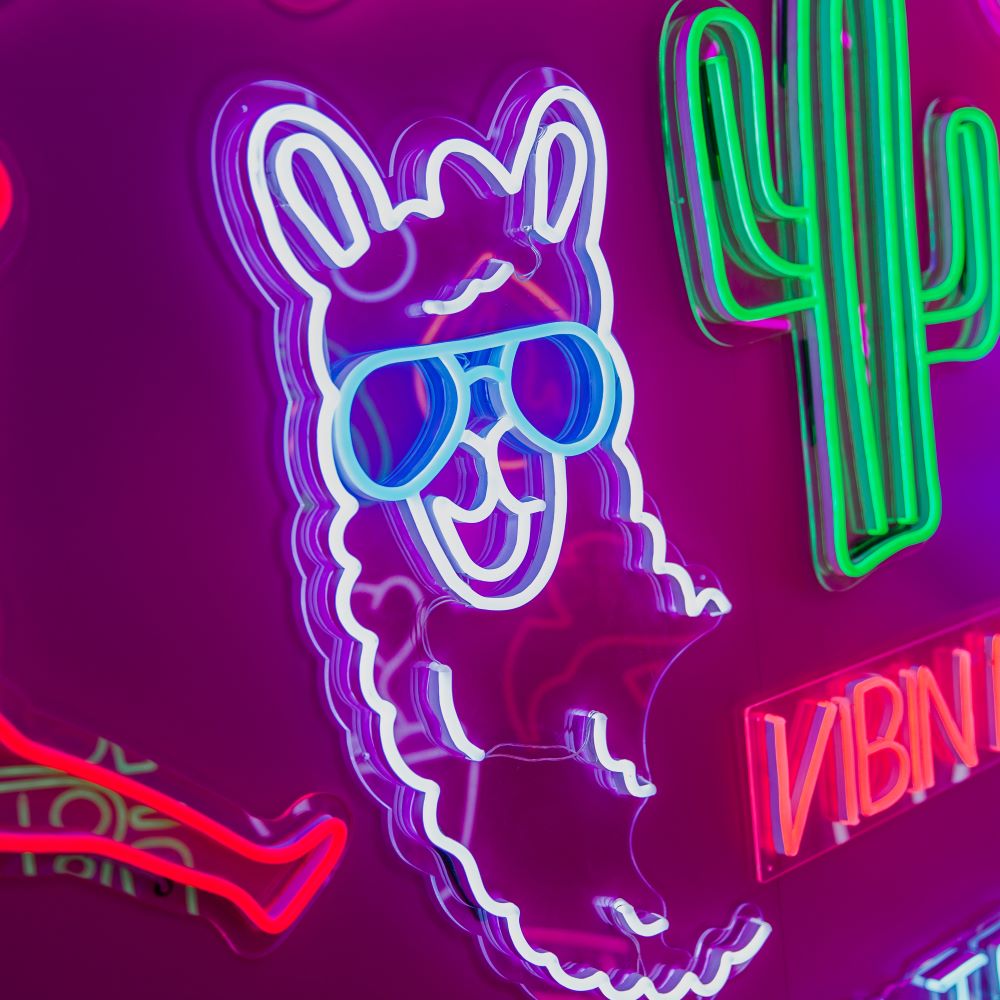 Llama neon light shown on a chair against a green wall - photo from CustomNeon.com