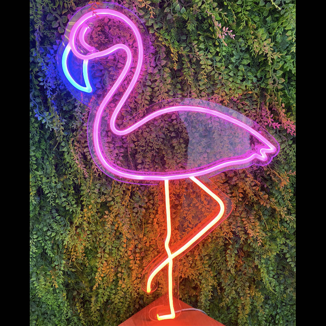 Multi-colored Flamingo in 8mm LED Neon Flex shown against a green wall - photo from CustomNeon.com