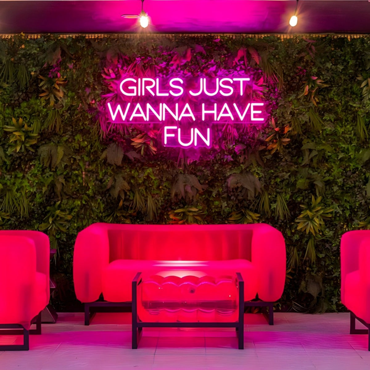 Girls Just Wanna Have Fun hot pink LED neon sign on a lush greenery wall in an outdoor seating area - CUSTOM NEON™ x SOMERLED COLLECTION