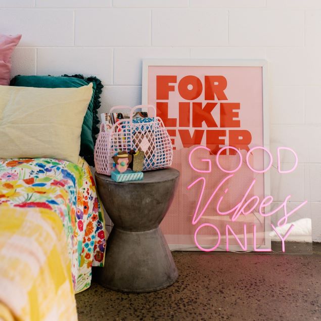 Good Vibes Only neon sign in pink with a pink jacket so it looks great both on and off - shown  in a bedroom - from Custom Neon®