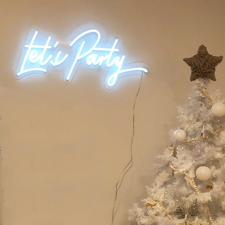 Let's Party white LED neon sign shown above Christmas tree - Custom Neon® @customneon