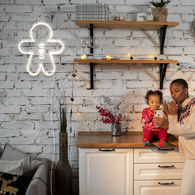 Light Up Gingerbread Man by CUSTOM NEON® shown in white on brick wall near Christmas lights & decorations
