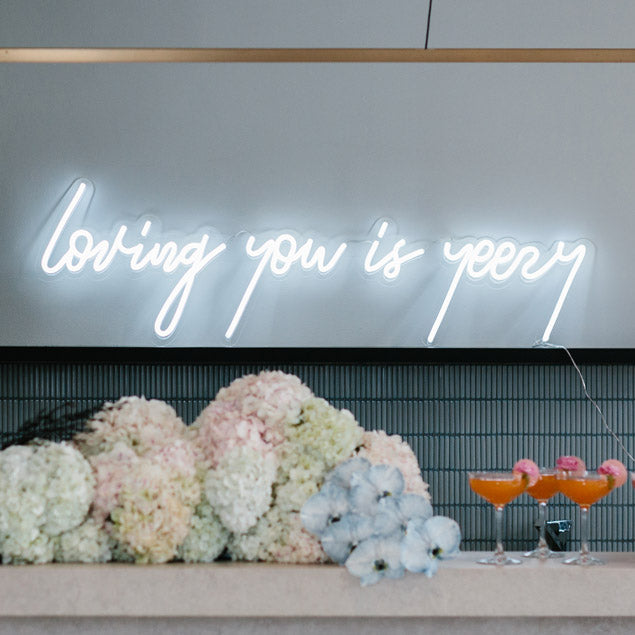 Loving you is yeezy LED neon wedding sign shown in white behind the bar - photo from CustomNeon.com