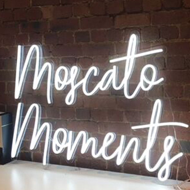 Moscato Moments white bar light shown against a brick wall - from Custom Neon®