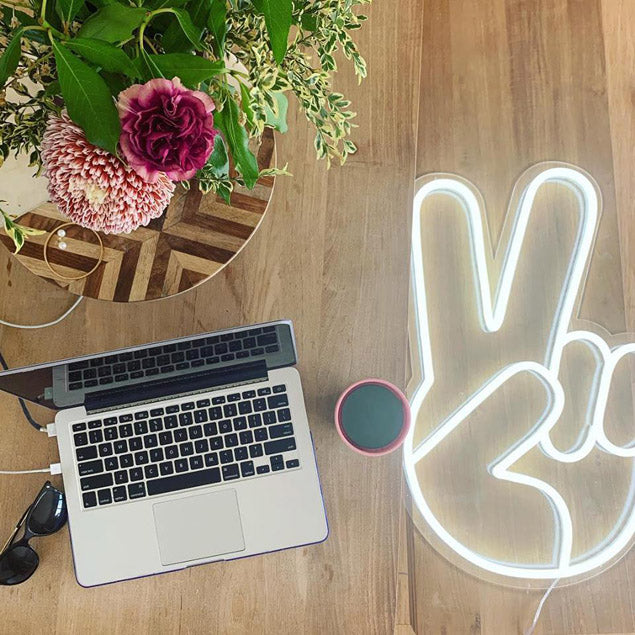 LED Neon Peace Sign Light shown on wooden floor - Photo CustomNeon.com