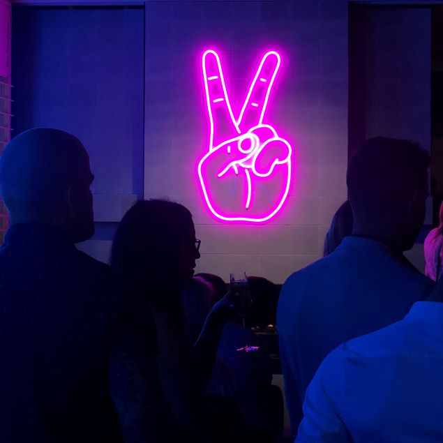 Neon Peace Sign aesthetic neon light shown wall mounted in a bar - from Custom Neon®