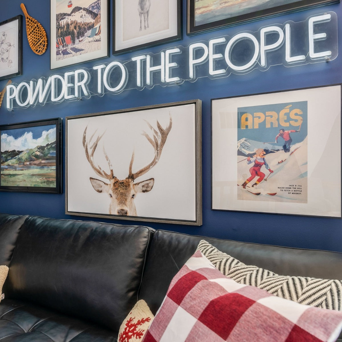 Powder to the People white LED neon sign on a blue feature wall surrounded by framed paintings and prints of mountain scenes - CUSTOM NEON™ x SOMERLED COLLECTION