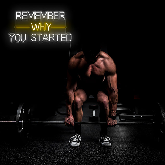 Remember Why You Started pre-designed CUSTOM NEON® sign in white & warm white shown wall mounted in a gym behind a man lifting weights