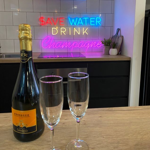 Save Water Drink Champagne neon bar sign shown in a kitchen - from Custom Neon