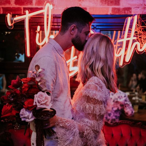 Til Death LED neon sign shown behind the happy couple at a wedding - photo from CustomNeon.com