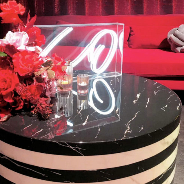 XO tabletop LED neon sign in acrylic box shown on a table during an event - photo from CustomNeon.com