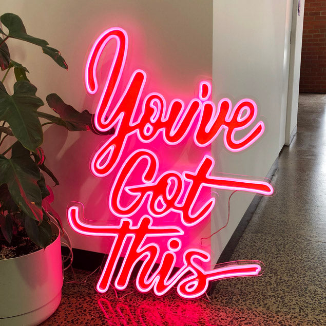 You've Got This pink LED neon motivational sign with red UV print from Custom Neon®  shown on an office floor